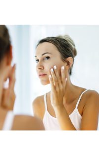 women after emsculpt treatment looking in mirror