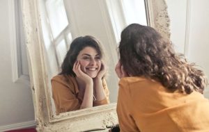 women smiling at her lip lines in the mirror